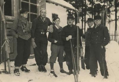 [Photograph of six unidentified men standing in snow with skis]