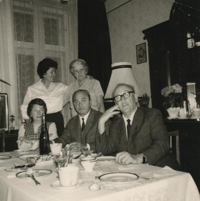 [Photograph of Leo and Julia Schmucker at table with unidentified people]