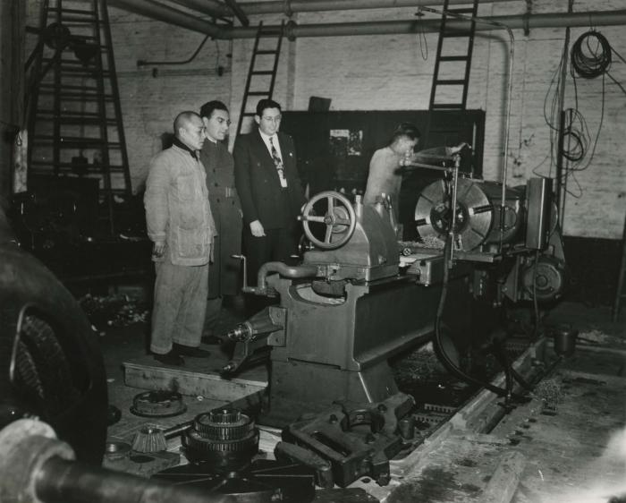 [Photograph of Manfred Gottfried with three unidentified men in a room full of machinery]